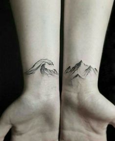 two hands with mountains tattoo on them