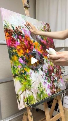 a woman is painting flowers on an easel