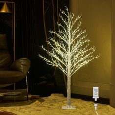 a white lighted tree in front of a brown leather chair with an outlet plugged into it