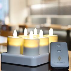 several lit candles sitting on top of a table next to a remote control