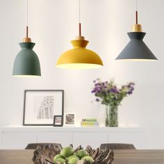 three hanging lights above a dining table with fruit on the plate in front of it