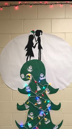 a christmas tree made out of paper and string lights with a silhouette of two people on top