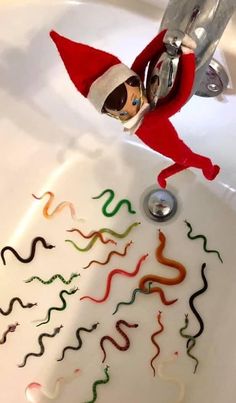 an elf is sitting in the sink with streamers coming out of it and water running from his mouth