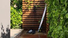 an outdoor shower in the middle of a garden with plants growing on it's sides