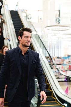 a man in a suit walking down an escalator with his hand in his pocket