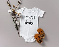 a baby's onesuit, sandals and t - shirt with the words 2020 baby printed on it