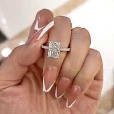 a woman's hand holding an engagement ring with white acrylic on it