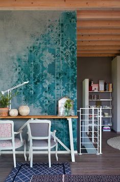 a living room with a table and chairs in front of a wall painted with blue flowers