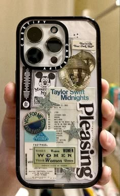 a person holding up a cell phone case with some stickers and buttons on it