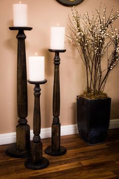 three candles are sitting next to each other on the floor in front of a wall