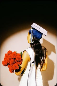 a woman with long hair and a graduation cap holding red roses in her left hand