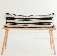 a black and white striped pillow sitting on top of a wooden bench