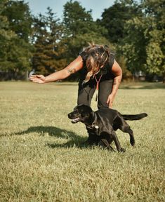 a woman is playing with her dog in the grass