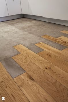 an empty kitchen with wood flooring and white cabinets