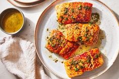 four pieces of fish on a plate with sauces and napkins next to it