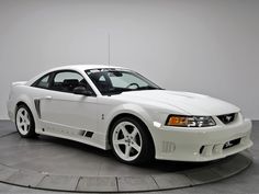 a white mustang sitting on top of a gray floor