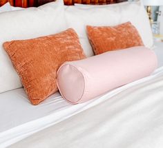 a bed with two pillows on top of it and a pink pillow in the middle