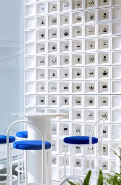 three blue and white stools are in front of a wall with many squares on it