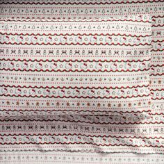 a white and red patterned curtain hanging on the side of a window