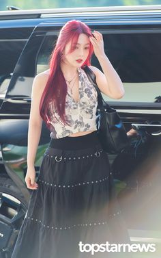 a woman with red hair is standing in front of a car