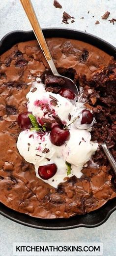 a skillet with chocolate pudding and ice cream in it, topped with cherries