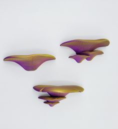 three pieces of art that are purple and gold on a white surface, with one piece in the shape of a whale's tail