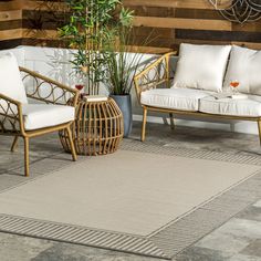 two chairs and a couch on a patio with plants in the corner next to them