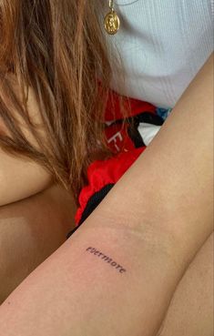 a woman with a small tattoo on her arm that reads,'strength'in cursive writing