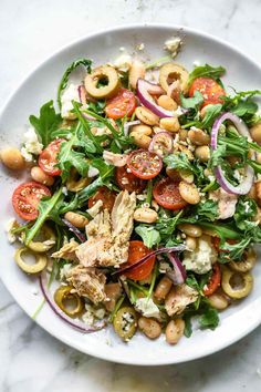 a white plate topped with salad and lots of veggies on top of it