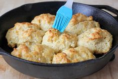 biscuits being cooked in a cast iron skillet with a blue spatula on top