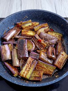 a pan filled with cooked vegetables sitting on top of a stove next to a wooden table