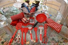 red kitchen utensils are sitting on a glass table