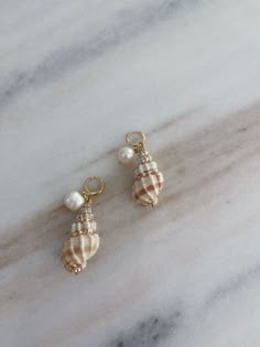 A pair of shell earrings with gold details and a hanging pearl perfect for the summer Shell Pearl Earrings, Pearl White Shell With Pearl Charm, Pearl Shell With Pearl Charm, Mother Of Pearl Shell With Pearl Drop, Shell-shaped Pearl Earrings With Pearl Charm, Pearl Shell Earrings With Pearl Charm, Ocean-inspired Pearl Drop Earrings, Ocean-inspired Pearl Shell With Pearl Drop, Ocean-inspired Pearl Drop Shell