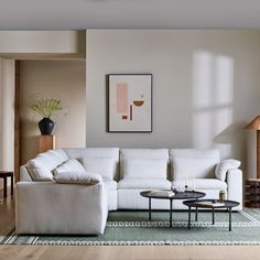 a living room with a white couch and coffee table in front of a painting on the wall