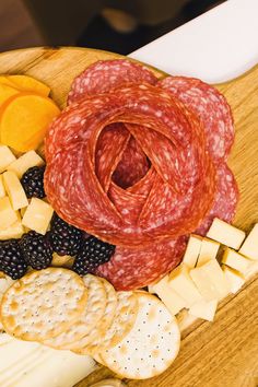 an assortment of cheeses, crackers, and meat on a wooden platter