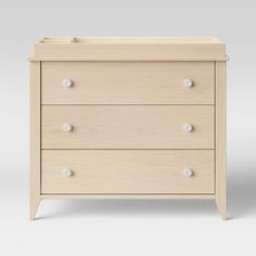 a baby crib with three drawers and white knobs