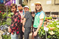 a group of young men standing next to each other in front of plants and flowers