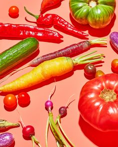 many different types of vegetables on a pink surface