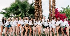 a group of young women standing next to each other in front of some palm trees