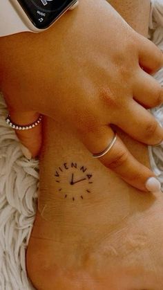 two people with tattoos on their feet and one has a small clock tattooed on the foot