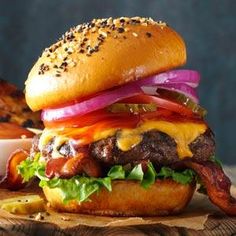 a cheeseburger with bacon, onions and lettuce on a wooden board