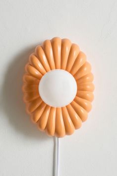 an orange flower shaped lollipop on a white wall