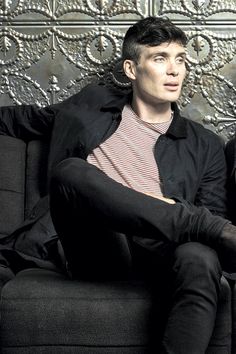 a man sitting on top of a couch in front of a metal paneled wall