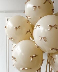 white balloons with gold bows on them in front of a door