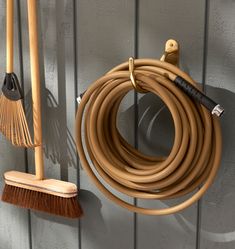 two brooms are hanging on the wall next to a hose holder and brush attachment