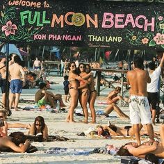 many people are on the beach and one person is holding up a sign that says full moon beach