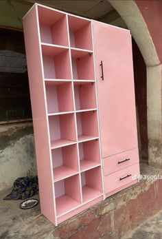 a pink bookcase sitting on the side of a building