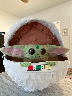 a star wars baby yoda inflatable egg on top of a bed with white ruffles