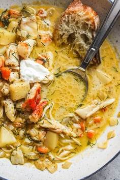 a bowl filled with chicken, potatoes and carrots next to a piece of bread