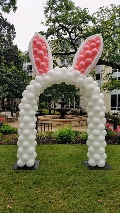 an inflatable bunny ears arch with pink and white balloons on the front lawn